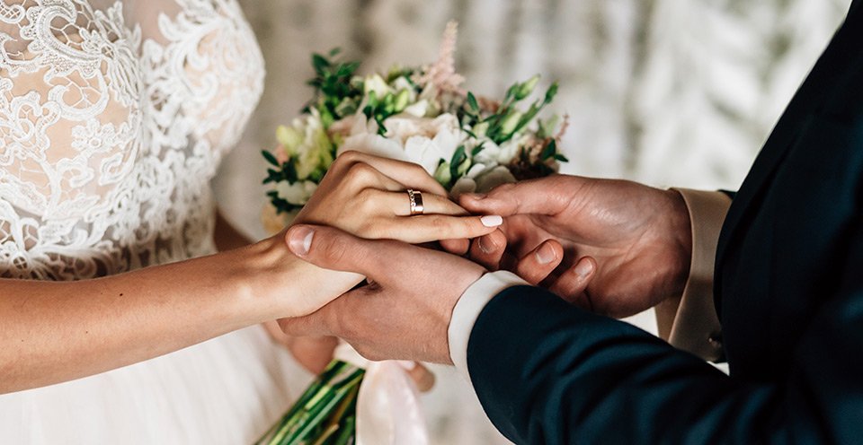 A bridegroom placing a wedding ring on his bride's wedding finger during their marriage ceremony