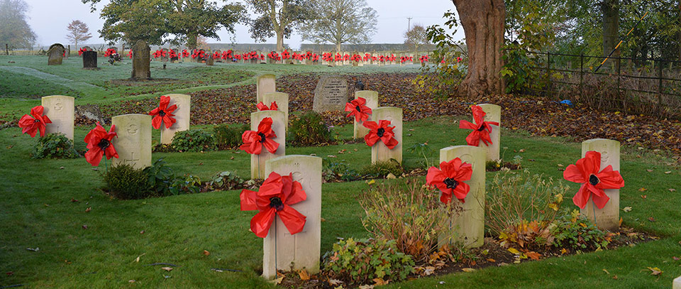 War graves in Scampton churchyard, decorated with large poppies for Remembrance Day