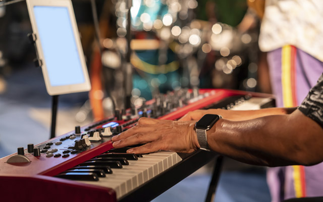 A close up of hands playing a keyboard in a church band